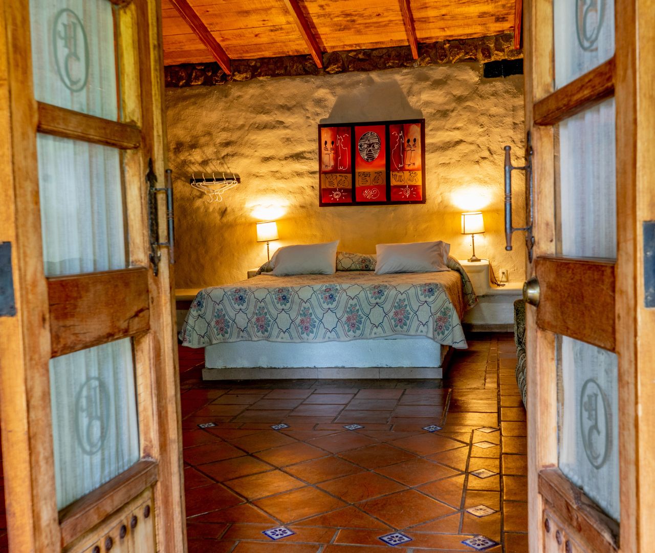 Recámara con cama matrimonial y muros de piedra